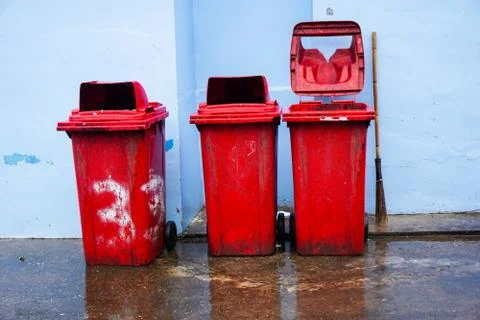 Old red trash can placed in the corner of the building Stock Photos