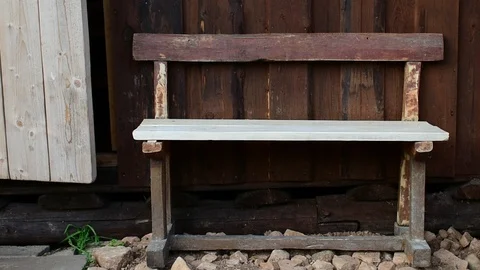 Old, repaired bench, against the wall of a wooden house Stock Footage 116886991