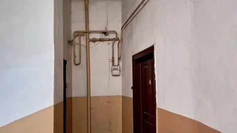 Old Residential Building Corridor with Exposed Gas Pipes and Doorway Vídeos de archivo 346441245