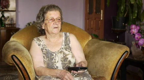 Old retired woman watching television in home Stock Footage