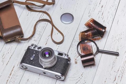 An old retro camera with a leather case, a magnifying glass and a film on whi Stock Photos