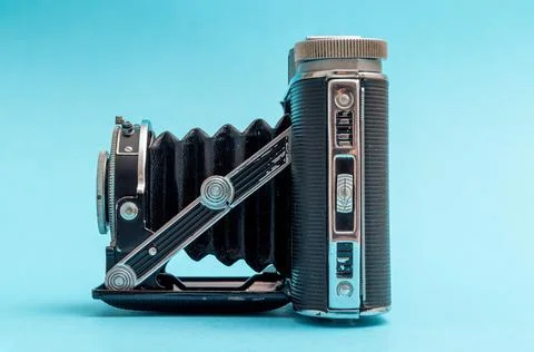 Old retro camera seen from side against blue pastel showing nostalgic feeling Foto stock