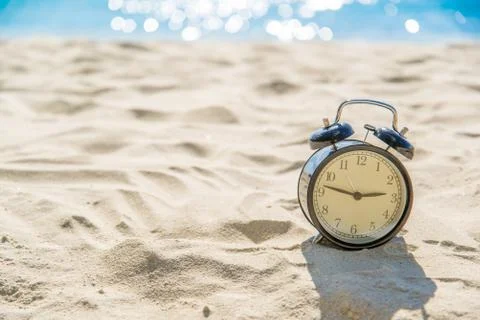 Old retro clock on sand beach over blurred of tropical blue sea background Stock Photos
