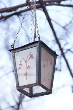 Old retro lantern with a pattern hanging on a chain in the garden. Stock Photos