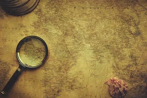 Old retro map of world is pressed with shells and magnifying glass.Vacation.. Stock Photos