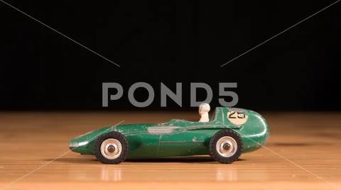 Old retro metal toy race car on wooden table with black background Stock Photos