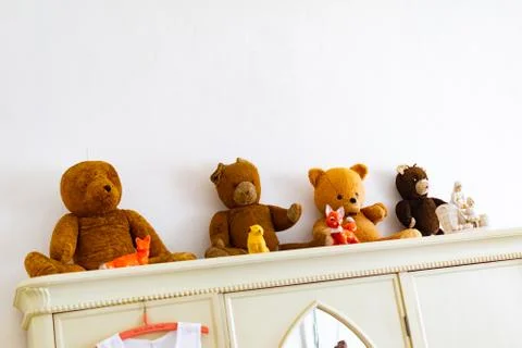 Old retro teddy bears looking from the cabinet in room for kids Stock Photos