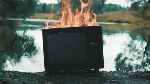 Old retro TV is on fire next to a pond. Concept of post apocalypse, surrealism Stock Footage 161636742