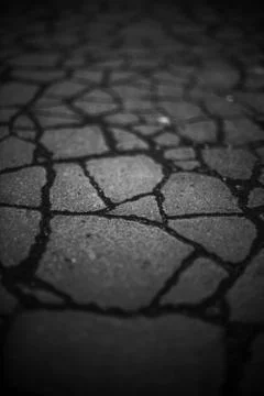 Old road dark surface made of old asphalt with cracks. Stone texture. Foto stock