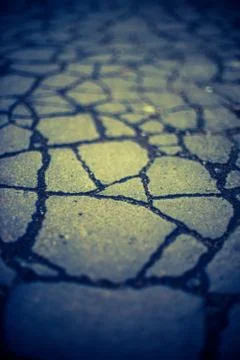 Old road surface made of old asphalt with cracks. Dark blue yellow tone. 스톡 사진