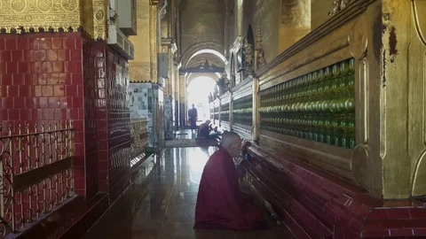 Old robed monk sits and prays on floor at Mahamuni Temple, Mandalay, Myanmar Vídeos de archivo 79423381