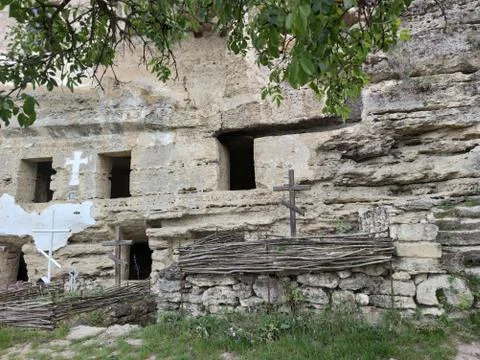 Old rock monastery. Empty window openings. Wooden cross. Wattle. Stock Photos