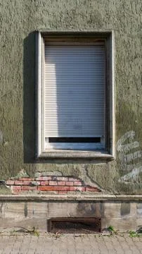 Old roller-shuttered window in a crumbling brick wall Stock Photos