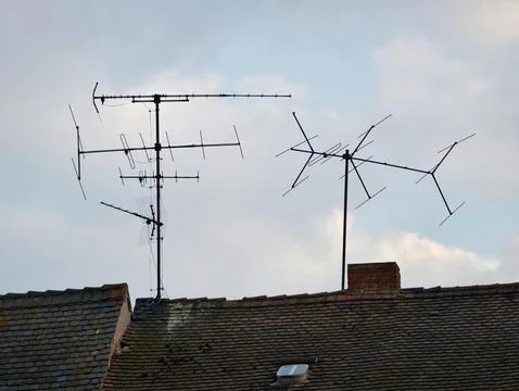 Old roof with antenna array. Rusty metal antennas atop aged tile roofing ag.. 写真素材