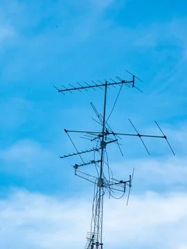 Old rooftop television antenna with multiple elements against clear blue sk.. Stock Photos