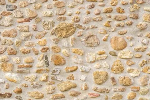 Old rough stone wall made of various square natural stones in beige, gray and Stock Photos