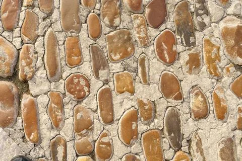 Old rough stone wall made of various square natural stones in beige, gray and Stock Photos