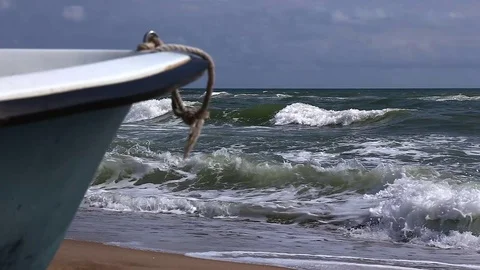 Old row boat on the sandy beach. Windy weather, waves in the sea bay Stock Footage 80530530