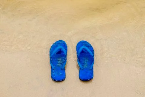 Old rubber flip flops on the sandy beach of the lake. Stock Photos