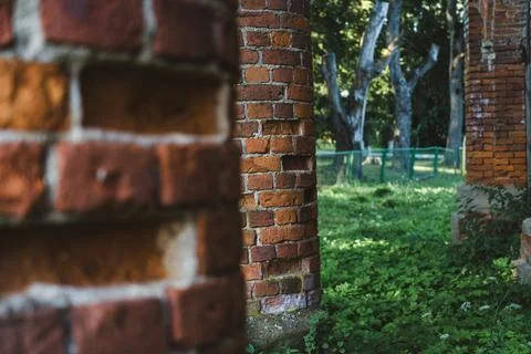Old, ruined red brick columns. The entrance to the old, ruined stable Stock Photos
