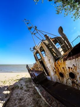 An old ruined ship sits rusting on the shore. Stock Photos