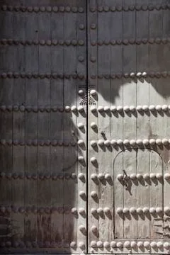 Old run down medieval door with iron spikes in the sun Stock Photos