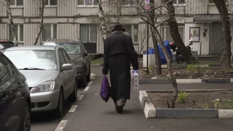 Old Russian man walking down the street with product packages in Moscow during Stock Footage 139831842