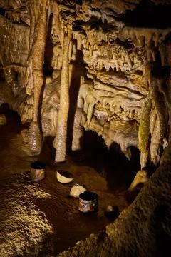 Old rusted drinking cups on ground of cave surrounded by stalagmites and Stock-Fotos