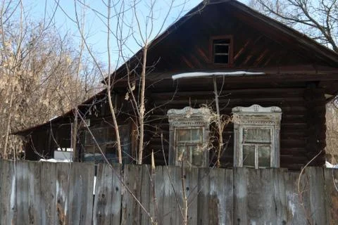 Old rustic abandoned house with figured platbands and wooden fence Stock Photos