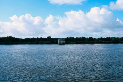 An   old   rustic   building   sinks   into   blue   water Stock Photos