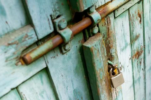 Old rustic door with new silver padlock. Stock Photos