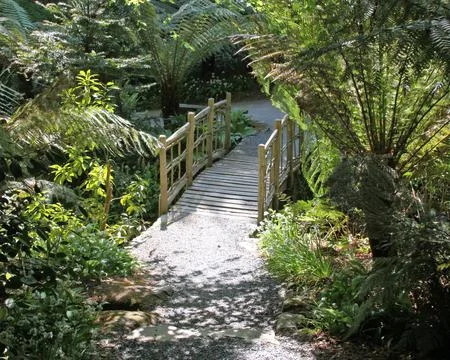 An old rustic fence over a tiny stream in an English country garden Stock Photos