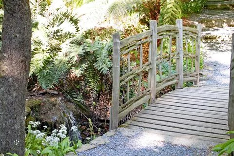 An old rustic fence over a tiny stream in an English country garden Stock Photos