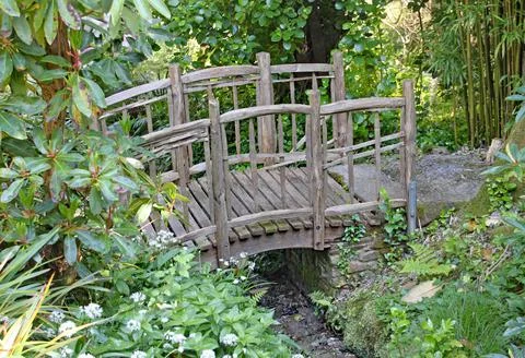 An old rustic fence over a tiny stream in an English country garden in Devon, Stock Photos