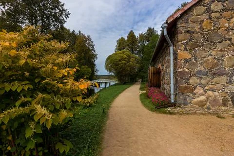 An old rustic stone barn for storing grain and grain near an earthen path on  Stock Photos