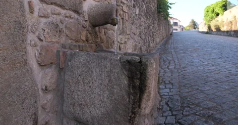 Old rustic stone drinking fountain in cobblestone street in rural Portugal Stock Footage 134472434