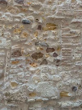 Old rustic stone wall with mixed rocks and ancient bricks Stock Photos