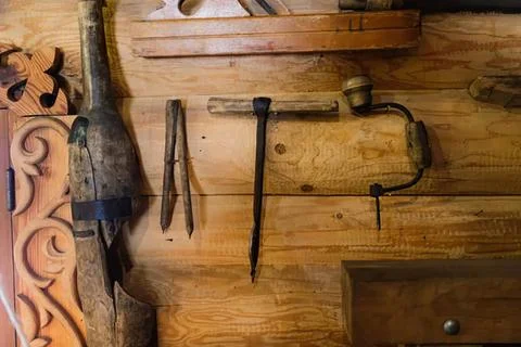 Old rustic tools hanging on wooden wall in a workshop 스톡 사진