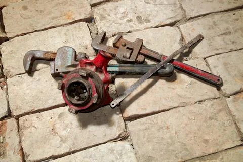 Old rustic used Pipe wrench, hexa blade, manual threading machine on brick .. Stock Photos