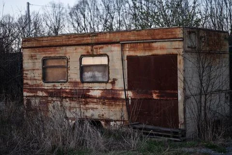 Old rusty abandoned construction trailer in a field at twilight. Stockfoto's