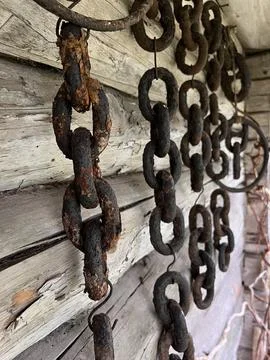 Old rusty anchor chains hanging on a barn wall Stock Photos