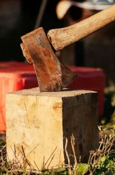 Old rusty axe stuck in a block of wood used for chopping other wood Stock Photos