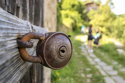 Old rusty barn lock. Closed lock on the metal handle of a wooden door. Close-up Stock Photos