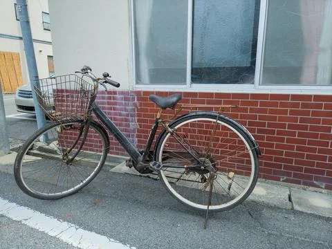 Old Rusty Bicycle Parked Outside a Building in Hokuei, Japan Foto stock
