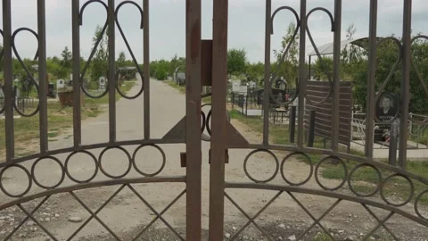 Old rusty brown gates. Blocking exit on gloomy graveyard. Abandoned cemetery Stock Footage 143845537