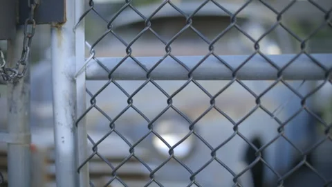 An old, rusty car sits behind a locked chain-linked fence. Stock Footage 144458287