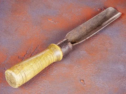 Old rusty carpenter chisel with wooden handle on an orange background Stock Photos