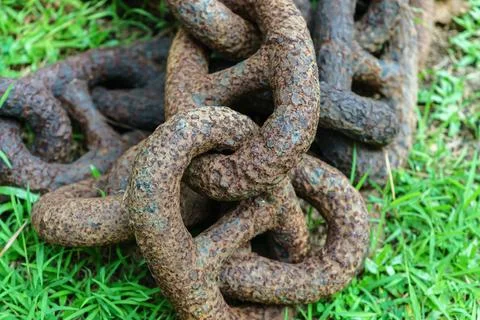 An old rusty chain lies on the grass Stock Photos