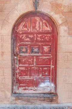 Old rusty closed dark red wooden door on yellow cement textured house wall Stock Photos