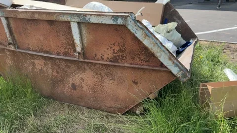 An old rusty container stands motionless in a field overgrown with tall grass Stock Footage 316387803